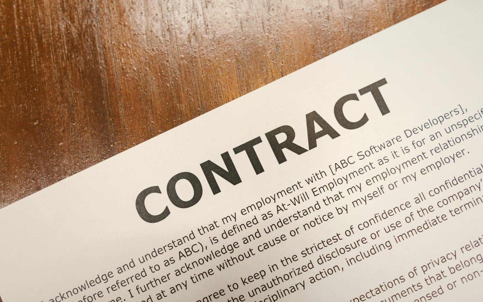 Printed employment contract document with at-will terms lying on a wooden table